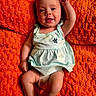 baby, infant, smiling, happy, child, portrait, clothing, dress, diaper, orange_blanket, texture, skin, face, arm, legs, lying_down, cute, indoors, person, young_child