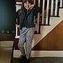 child, girl, smile, pose, indoor, staircase, denim_vest, patterned_pants, black_boots, carpet, wood_paneling, railing, ghost_decorations, happy, fashion, young_person, casual_clothing, portrait, person, home