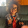 Julius is registered to the contest to win money with this photo: child, smiling, glasses, costume, tie, chocolate, curly_hair, sofa, indoor, happy, face_paint, casual_clothing, portrait, hand, wood_paneling, window, light, couch, playful, young