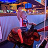 Whyatt is registered to the contest to win money with this photo: baby, child, toddler, smiling, waving, riding, rocking_horse, toy, restaurant, indoor, portrait, face, blond_hair, suspenders, bow_tie, seated, playful, colorful_lighting, wooden_furniture, entertainment
