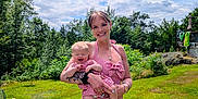 Millie is registered to the contest to win money with this photo: baby, child, clouds, dress, grass, greenery, happy, holding, nature, outdoor, person, portrait, red_checkered_clothing, sky, smiling, summer, sunny, tattoos, trees, woman