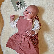 Iris a rejoint le concours — aidez-le/la à gagner de superbes lots ! baby, card, celebration, child, clothing, cute, happy, illustration, indoors, infant, lying_down, one_month, person, pinafore, pink_dress, portrait, small_fist, smiling, white_rug, wooden_floor