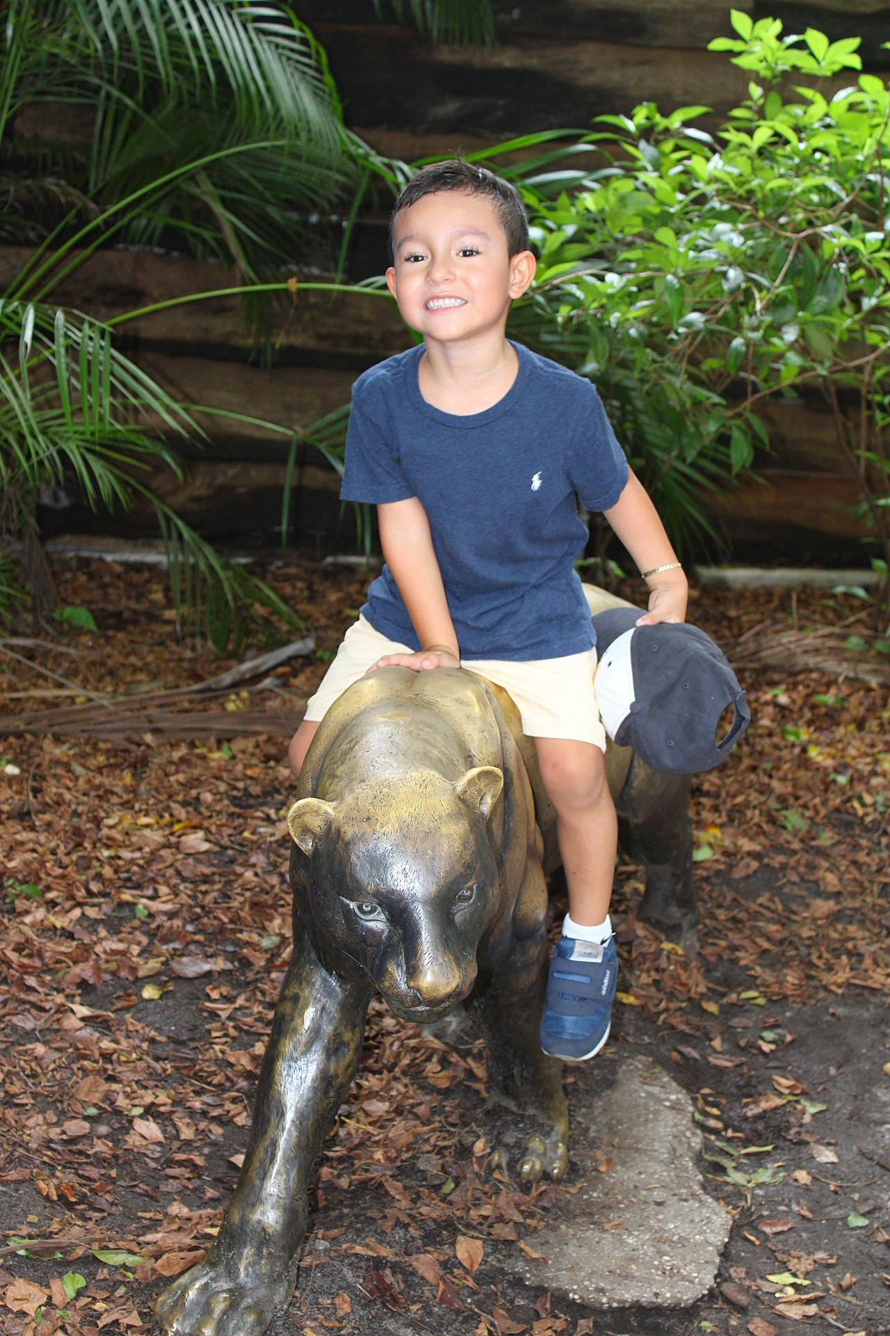 Carlos is registered to the contest to win money with this photo: adaptation, boot, child, foot, galapagos_tortoise, grass, human_leg, joy, jungle, leisure, person, plant, reptile, sculpture, shorts, soil, t_shirt, terrestrial_animal, thigh, toddler