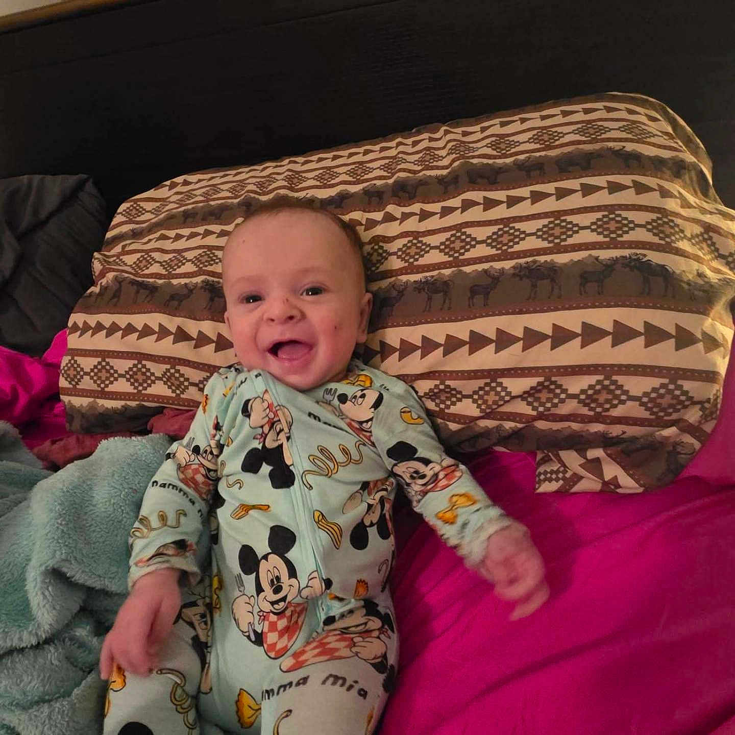 Toby joined the competition — help win amazing prizes! baby, bed, blanket, curtain, cute, feet, hand, happy, headboard, indoors, infant, linens, lying_down, mickey_mouse, pajamas, pattern, pillow, pink_sheet, portrait, smile
