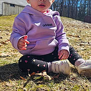 Kehlani is registered to the contest to win money with this photo: toddler, child, outdoor, grass, sunlight, hoodie, purple, adidas, curious, face, person, trees, house, blue_sky, leggings, heart_pattern, shoes, sitting, daylight, nature