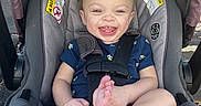 Kehlani is registered to the contest to win money with this photo: toddler, child, car_seat, smiling, happy, baby, seatbelt, foot, blue_clothing, outdoor, sunlight, hair, face, infant, playful, sitting, safety_harness, cute, skin, portrait