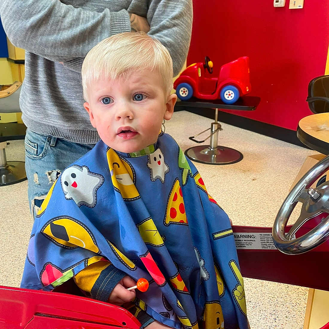 Elias is registered to the contest to win money with this photo: baby, barbershop, blanket, car, clothing, coat, face, haircut, hairdresser, head, indoors, jeans, machine, pants, person, photography, portrait, transportation, vehicle, wheel