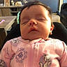 Amelia is registered to the contest to win money with this photo: newborn, baby, infant, sleeping, portrait, face, pink_onesie, floral_clothing, indoors, living_room, chair, furniture, sunlight, warm_lighting, closeup, peaceful, family_home, child, head, photograph