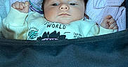Amelia is registered to the contest to win money with this photo: baby, infant, child, stroller, portrait, face, eyes, hair, clothing, sweater, knitwear, seated, indoor, cozy, blanket, padded_seat, calm, alert, photography, text_on_clothing