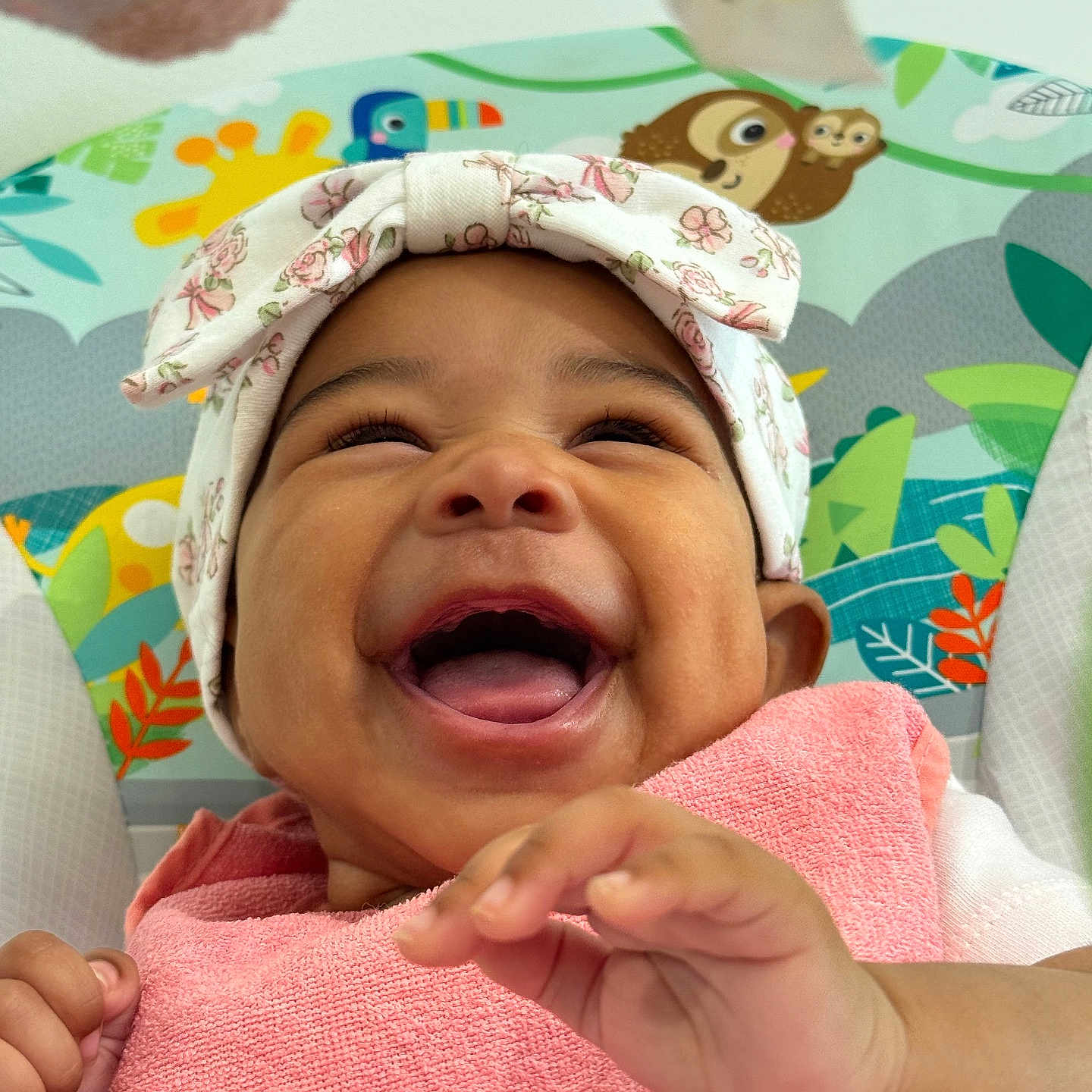 Paige is registered to the contest to win money with this photo: animal_print, baby, child, closeup, colorful_background, cute, expression, face, hand, happy, headwrap, infant, joy, pink_towel, playful, portrait, seated, skin, smiling, toddler