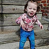 Malaya is registered to the contest to win money with this photo: toddler, child, flower_shirt, blue_jeans, black_socks, wooden_stairs, brick_wall, concrete, outdoor, standing, happy, smiling, portrait, young_child, casual_clothing, sunny_day, playful, hair_up, person, daylight