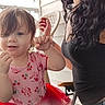 casual_wear, child, curly_hair, cute, daylight, glasses, hand_gesture, happy, outdoor, person, pink_clothing, plastic_chair, porch, portrait, red_tutu, seated, smile, toddler, woman, young_child
