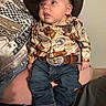 baby, child, cowboy_hat, jeans, boots, belt, western_shirt, indoor, person, infant, cute, portrait, sitting, clothing, hat, face, young_child, casual, people, closeup