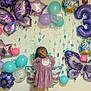 Xianah is registered to the contest to win money with this photo: child, birthday, balloons, butterfly_balloons, purple_dress, tiara, smiling, decorations, party, celebration, wall, girl, happy, festive, colorful, indoor, cute, posing, holiday, fun