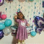 child, girl, birthday, balloons, unicorn_headband, purple_dress, cat_design, smiling, celebration, party, decorations, stars, butterfly_balloon, flower_balloon, standing, happy, indoor, posing, festive, colorful