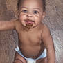 baby, child, diaper, chocolate, messy, floor, wooden_floor, skin, mouth, tongue, arm, hand, sitting, indoor, cute, infant, young_child, smiling, happy, person