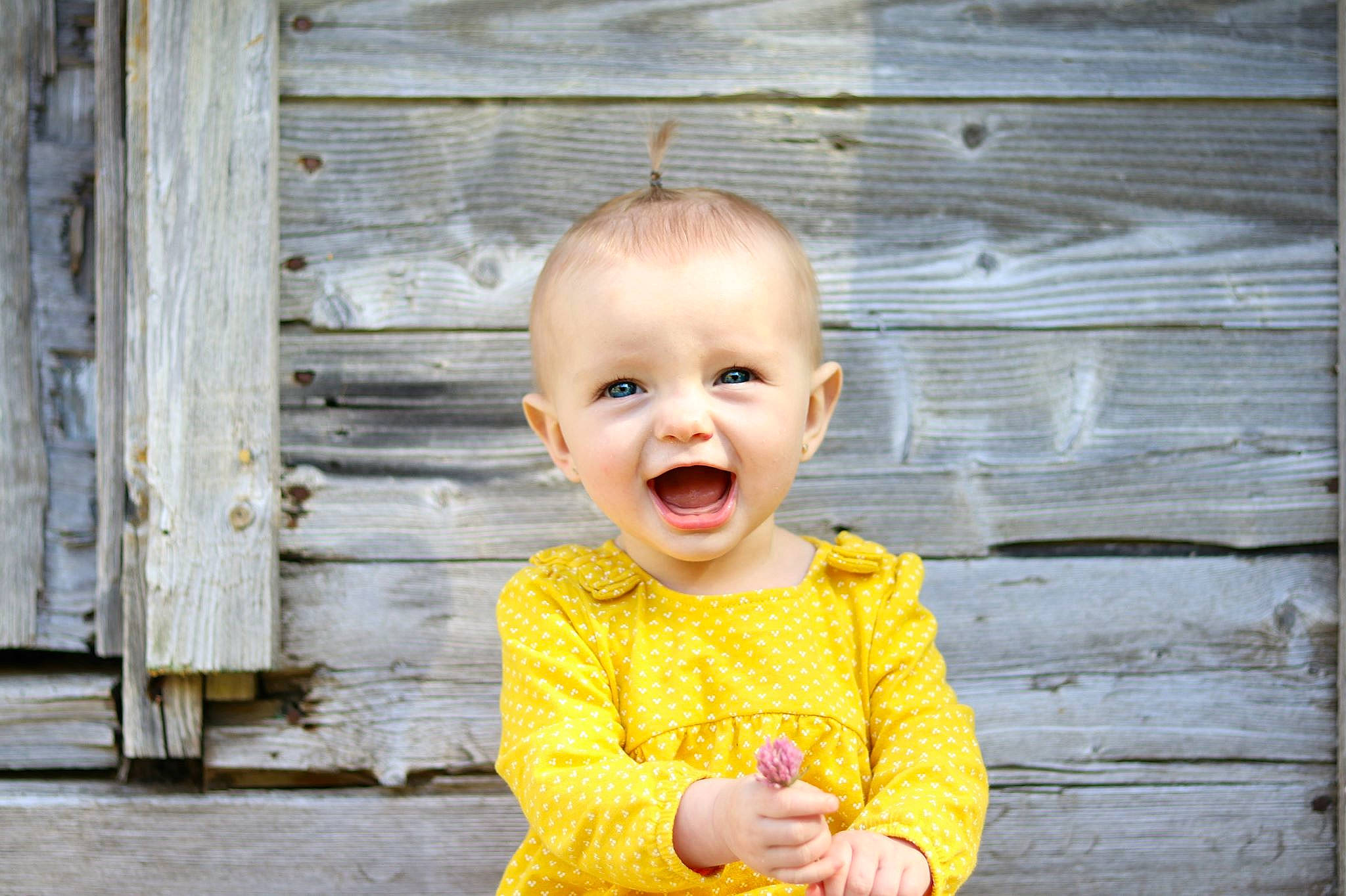 Layla-rose joined the competition — help win amazing prizes! baby, baby_laughing, baby_toddler_clothing, cheek, child, child_model, facial_expression, happy, person, photograph, photography, portrait, portrait_photography, smile, standing, toddler, wood, yellow