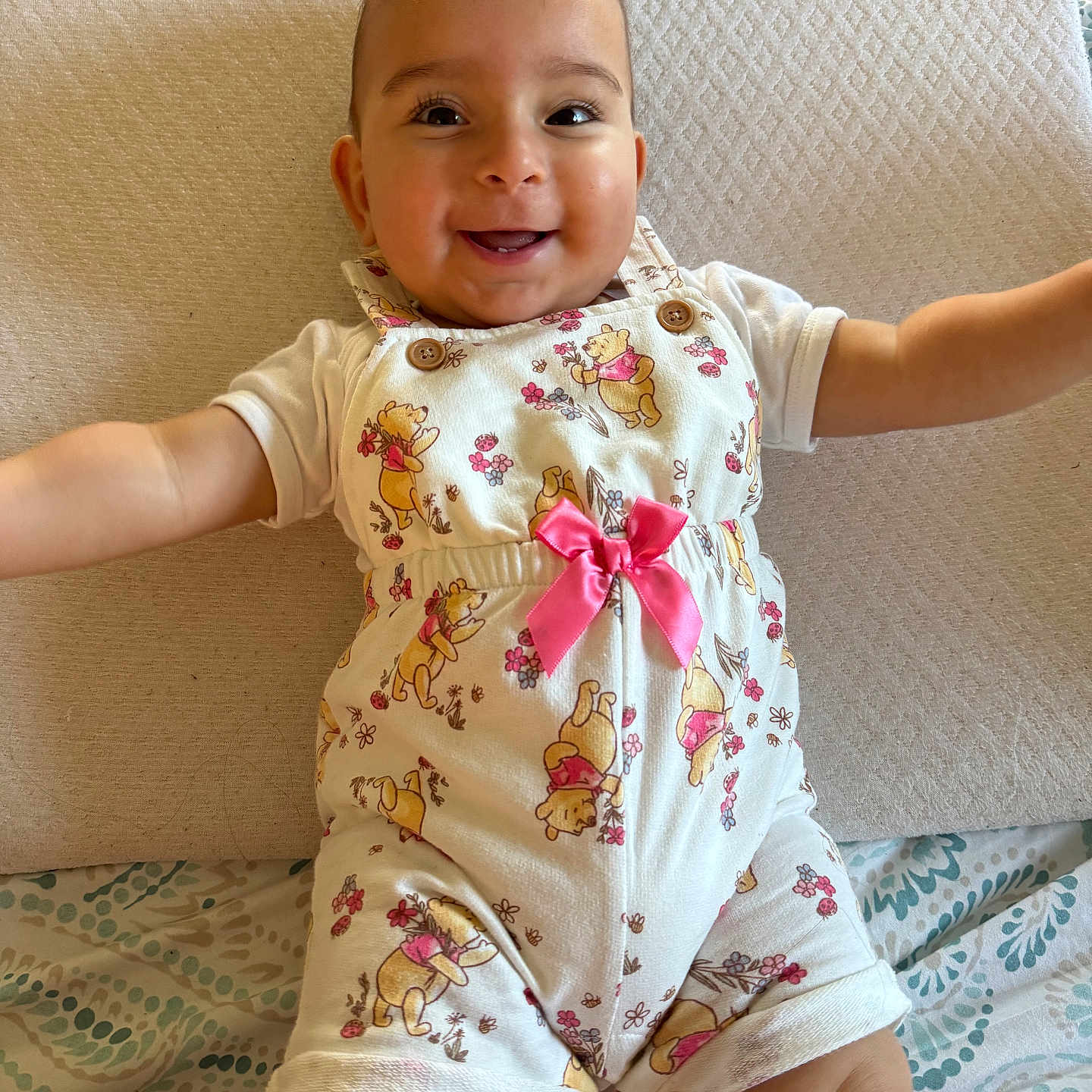 Kimiya joined the competition — help win amazing prizes! arms_outstretched, baby, child, clothing, cushion, cute, face, happy, indoors, infant, lying_down, patterned_blanket, person, pink_bow, playful, portrait, romper, smiling, soft_lighting, winnie_the_pooh
