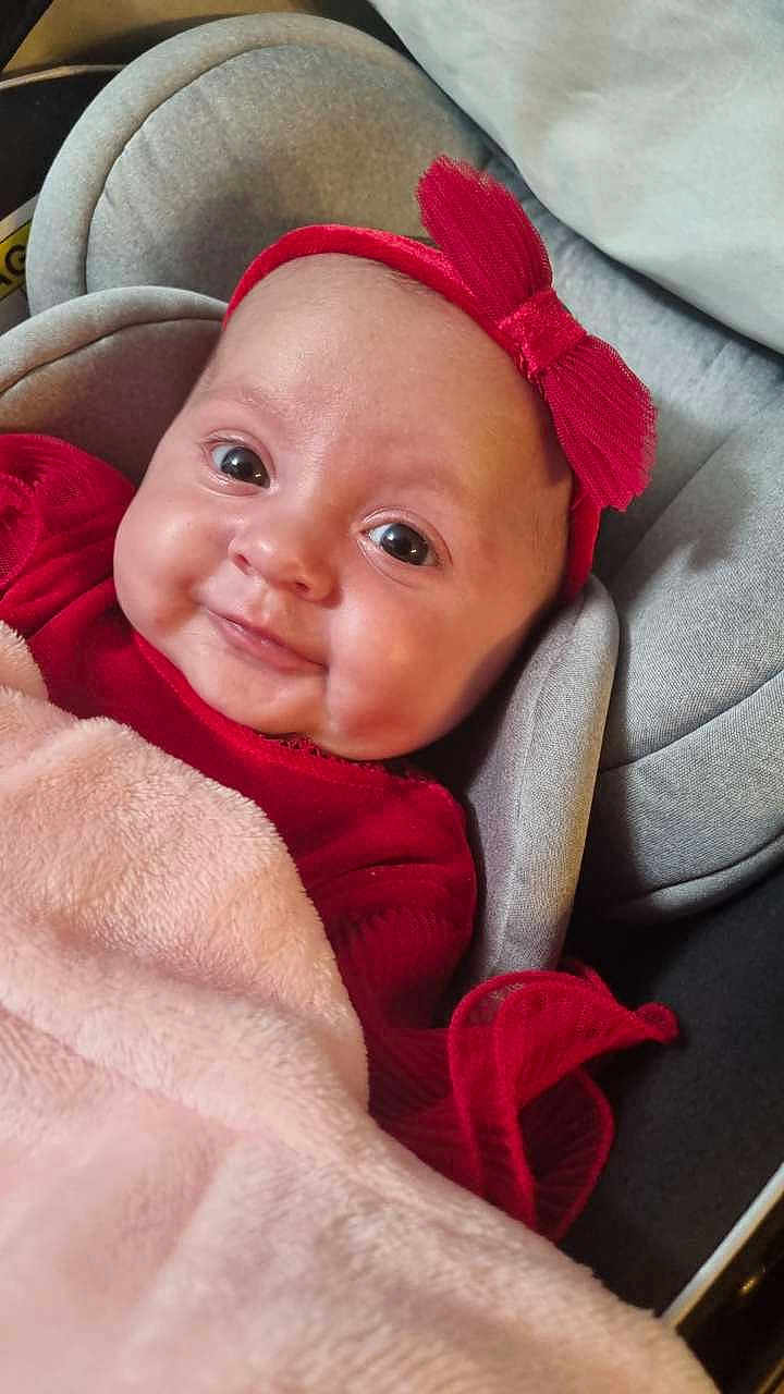 Liyana participe au concours pour gagner de l'argent avec cette photo : baby, infant, smile, red_bow, red_clothing, blanket, car_seat, face, headband, child, cute, indoors, portrait, young_child, soft_texture, comfort, happy, closeup, person, seat