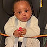baby, car_seat, infant, white_clothing, pacifier, straps, wide_eyes, curious_expression, child, toddler, seatbelt, sitting, indoor, cute, young_child, person, portrait, warm_clothing, hands, face