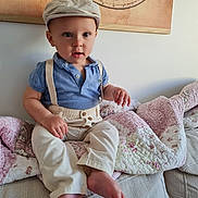 Sacha participe au concours pour gagner de l'argent avec cette photo : toddler, child, boy, blue_polo, beige_pants, suspenders, striped_cap, couch, quilt, floral_pattern, indoor, portrait, cute, curious, seated, vintage_map, wall_art, barefoot, light, home
