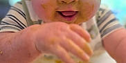 Beck is registered to the contest to win money with this photo: baby, cheeks, child, close_up, clothing, cute, face, feeding, food, hand, happy, high_chair, indoors, infant, meal, messy, smile, striped_shirt, table, tongue