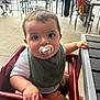Beck joined the competition — help win amazing prizes! arm, baby, bib, casual, child, curious, cute, face, hand, high_chair, indoor, infant, pacifier, person, restaurant, seated, short_hair, skin, table, wooden_chair