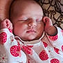 baby, child, closeup, cradling, cute, daisy_pattern, face, hand, indoor, infant, newborn, onesie, patterned_clothing, peaceful, person, portrait, resting, sleeping, soft_skin, strawberry_pattern