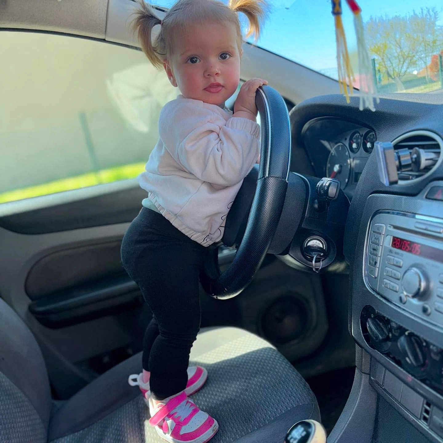 Malyana a rejoint le concours — aidez-le/la à gagner de superbes lots ! black_pants, car_door, car_interior, child, clothing, cute, dashboard, daylight, gear_shift, indoor, person, pigtails, pink_shoes, seat, steering_wheel, sunlight, toddler, vehicle, white_sweater, window