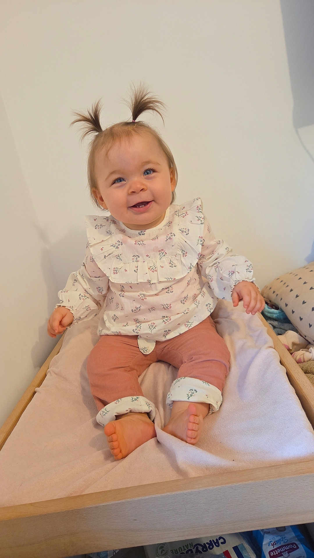 Mya Ladune participe au concours pour gagner de l'argent avec cette photo : baby, barefoot, blanket, changing_table, child, cute, floral_clothing, furniture, happy, indoor, infant, person, pigtails, pink_pants, portrait, room, sitting, smiling, soft_lighting, wooden_frame