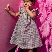 Nyla a rejoint le concours — aidez-le/la à gagner de superbes lots ! toddler, child, girl, dress, checkered, pink_feathers, feather_wall, wall, floor, socks, standing, indoor, curious, pose, portrait, young_child, fashion, colorful, cute, expression