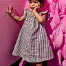 toddler, child, girl, dress, checkered, pink_feathers, feather_wall, wall, floor, socks, standing, indoor, curious, pose, portrait, young_child, fashion, colorful, cute, expression