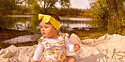Maielynn joined the competition — help win amazing prizes! baby, child, headband, yellow, floral_outfit, blanket, pond, water, trees, autumn, nature, outdoor, grass, sitting, cute, infant, peaceful, daylight, person, portrait
