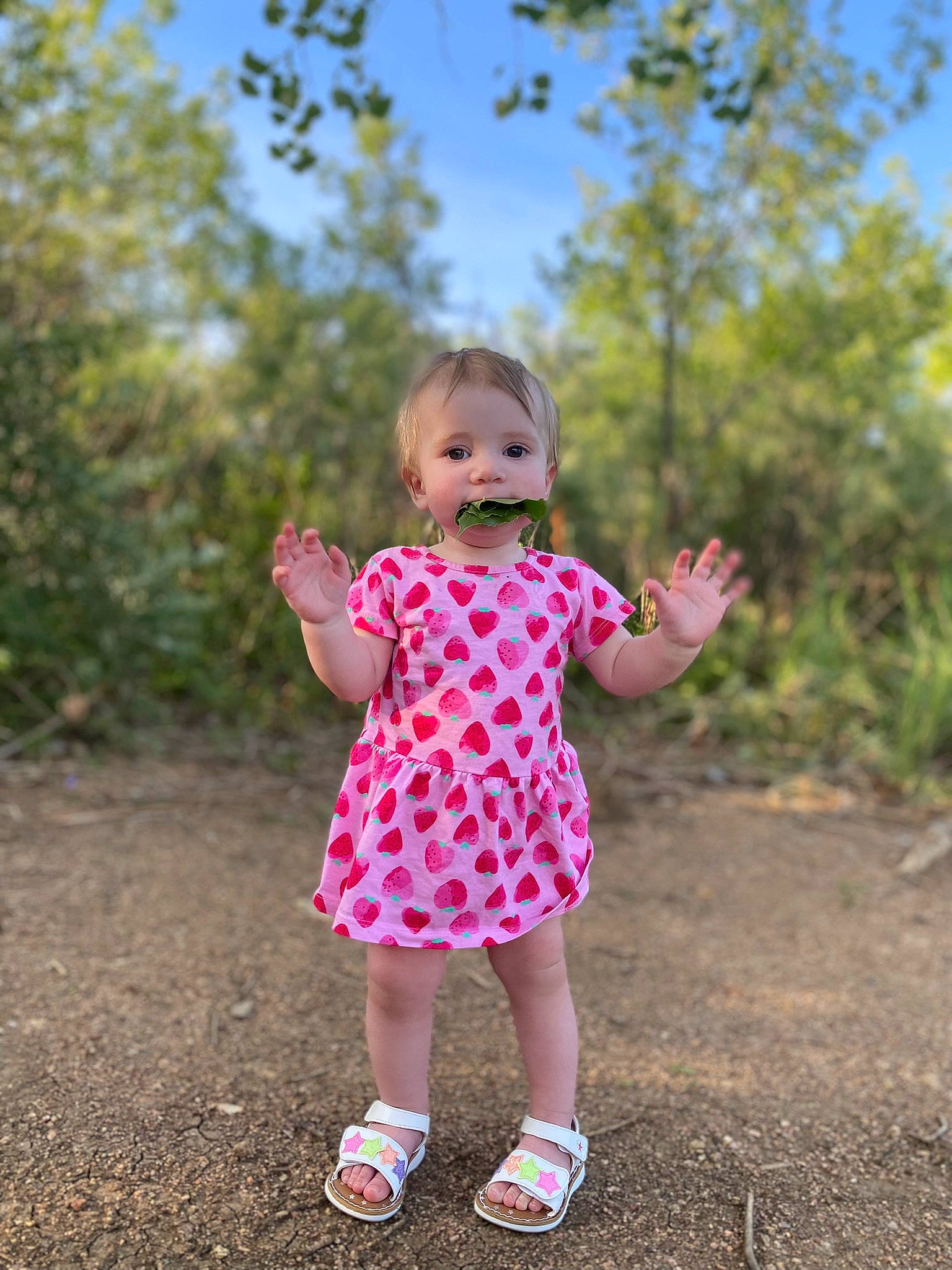 Arabelle is registered to the contest to win money with this photo: baby, baby_toddler_clothing, fun, gesture, grass, grassland, hand, happy, leisure, meadow, people_in_nature, person, pink, plant, sky, smile, standing, summer, toddler, tree
