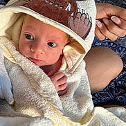 Noah is registered to the contest to win money with this photo: baby, towel, hood, hand, manicure, skin, face, eyes, expression, soft, fabric, comfort, newborn, person, indoor, closeup, cute, child, wrapped, resting