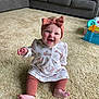 baby, child, smile, happy, sitting, carpet, headband, bow, dress, leggings, living_room, sofa, toy, floor, indoor, person, cute, infant, expression, home