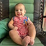 arms, baby, child, cushion, cute, feet, green_chair, happy, indoor, infant, legs, pacifier, person, portrait, red_and_white, relaxing, seated, smiling, striped_clothing, sunlight