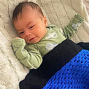 Lucas joined the competition — help win amazing prizes! baby, blanket, crochet, dinosaur_print, green_clothing, infant, lying_down, smile, soft_texture, sleepy, cozy, cute, child, face, head, person, portrait, resting, warm, indoors