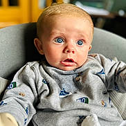 Leonardo joined the competition — help win amazing prizes! baby, blue_eyes, sweater, gray_chair, indoor, curious_expression, infant, clothing, soft_lighting, portrait, child, cute, sitting, young_child, face, person, close_up, cozy, background_blur, casual
