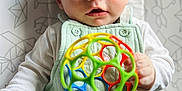 Leonardo joined the competition — help win amazing prizes! baby, infant, child, toy, ball, blue_eyes, overalls, white_shirt, hand, face, curious, lying_down, patterned_background, indoor, closeup, cute, playful, colorful_toy, portrait, young