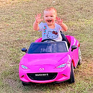 Aitana joined the competition — help win amazing prizes! toddler, child, smiling, happy, toy_car, pink_car, outdoor, grass, hello_kitty, shirt, baby, playing, waving, summer, daylight, vehicle, fun, cute, portrait, young_child