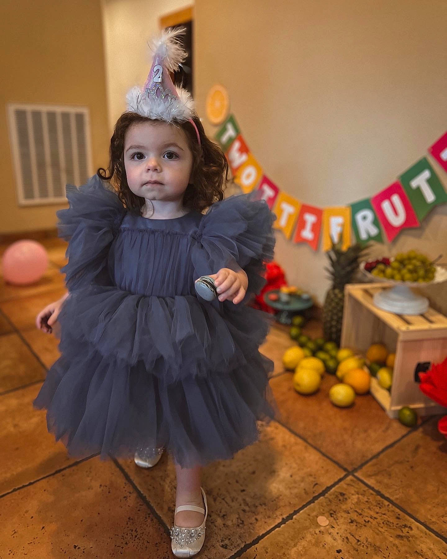 Mariana is registered to the contest to win money with this photo: child, costume, event, fashion_design, flooring, fruit, fun, fur, happy, party_supply, person, room, sandal, sitting, toddler, toy, tradition