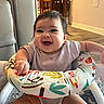 baby, baby_walker, carpet, cheerful, child, cute, expression, floor, furniture, happy, home, indoor, infant, living_room, person, playful, seated, shirt, smiling, young