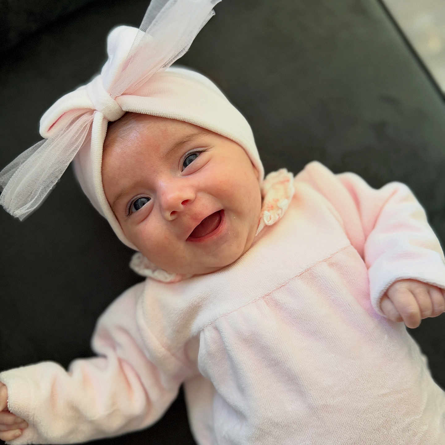 Sharell a rejoint le concours — aidez-le/la à gagner de superbes lots ! apparel, baby, bow, cheerful, child, closeup, cozy, cute, face, happy, headband, indoors, infant, lying_down, person, pink_clothing, portrait, smile, soft_texture, tulle