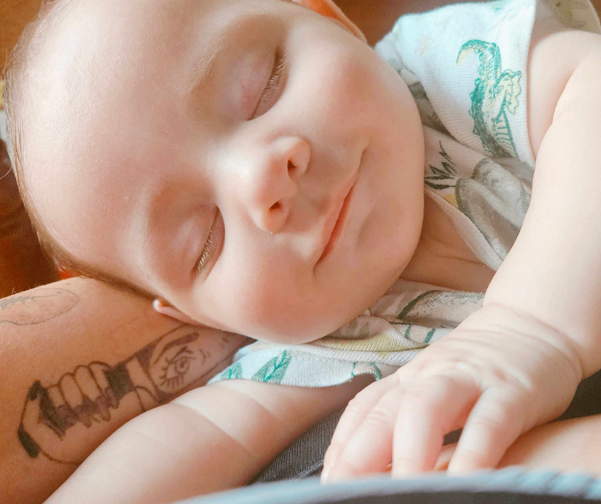 Goldie joined the competition — help win amazing prizes! baby, sleeping, smile, arm, tattoo, onesie, closeup, face, child, peaceful, skin, hand, resting, infant, cute, portrait, soft_light, relaxing, indoors, comfort