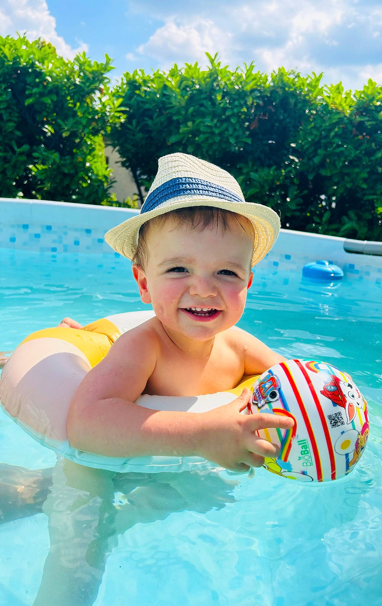 Thyago participe au concours pour gagner de l'argent avec cette photo : aqua, azure, blue, body_of_water, cap, cloud, green, happy, hat, headgear, joy, leisure, outdoor_recreation, person, plant, sky, smile, sun_hat, swimming_pool, toddler
