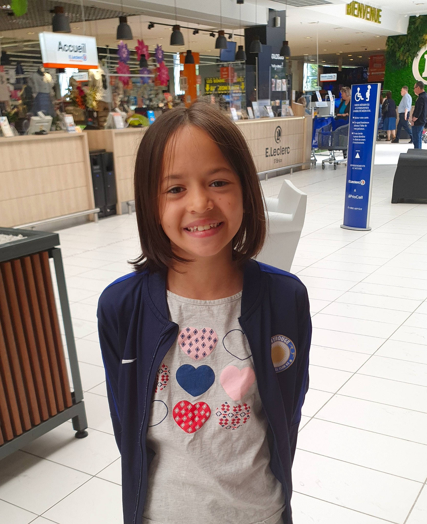 Kelly participe au concours pour gagner de l'argent avec cette photo : child, convenience_store, customer, electric_blue, event, flooring, fun, hairstyle, happy, head, joy, leisure, luggage_and_bags, person, recreation, retail, shopping, sleeve, smile, sportswear