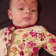 Morgan joined the competition — help win amazing prizes! baby, child, face, eyebrows, floral, onesie, clothing, lying_down, infant, skin, expression, person, cute, young, portrait, indoor, fabric, pattern, sleepwear, head