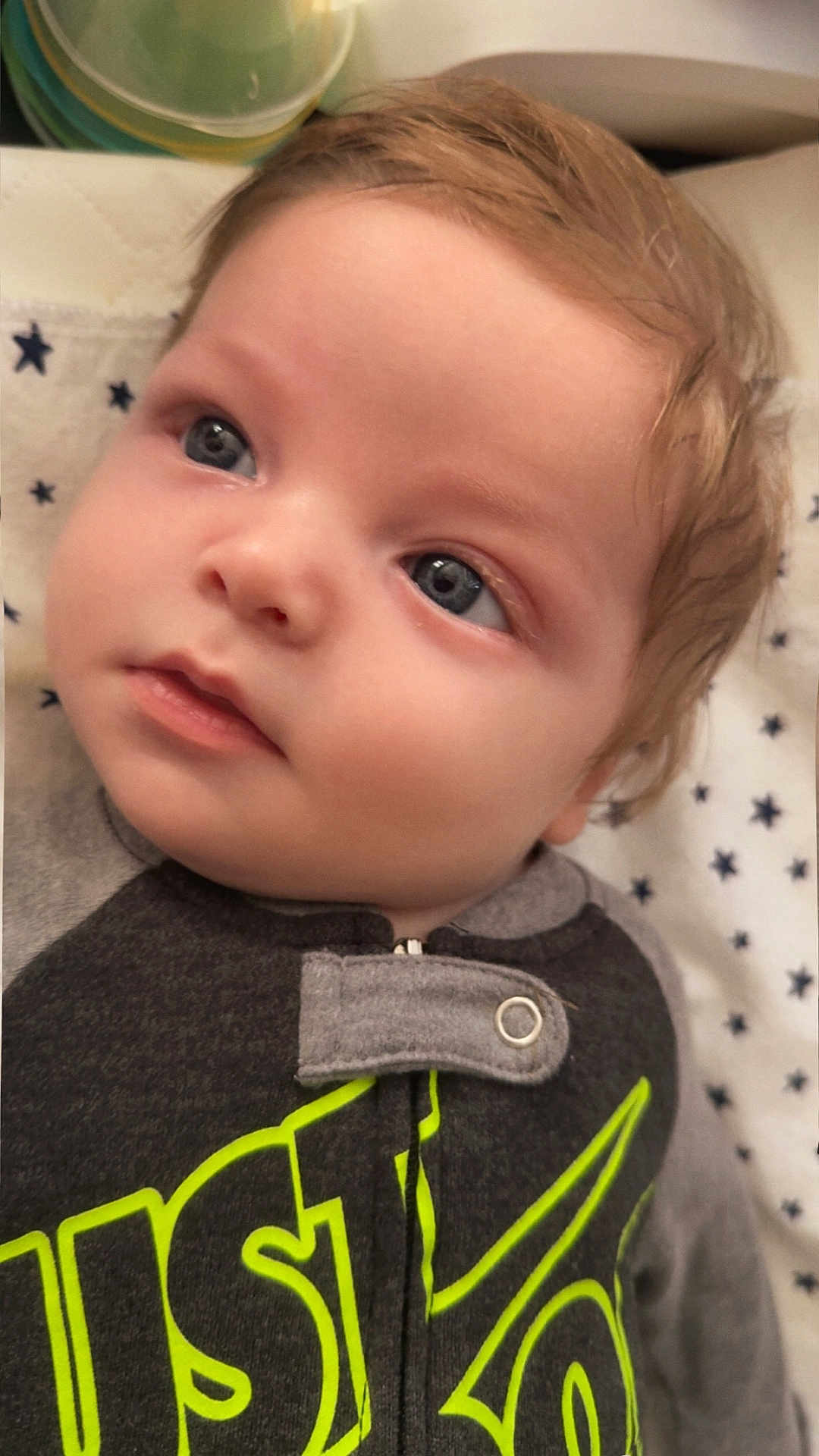 Eric joined the competition — help win amazing prizes! baby, infant, child, face, blue_eyes, light_hair, clothing, onesie, blanket, star_pattern, portrait, close_up, cute, young, toddler, sleeping_area, soft_lighting, indoor, calm, curious