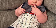 Jaxson is registered to the contest to win money with this photo: baby, infant, child, couch, sofa, clothing, striped_onesie, fingers_in_mouth, curious_expression, indoor, soft_lighting, plush_furniture, seated, barefoot, skin, head, face, person, cute, young